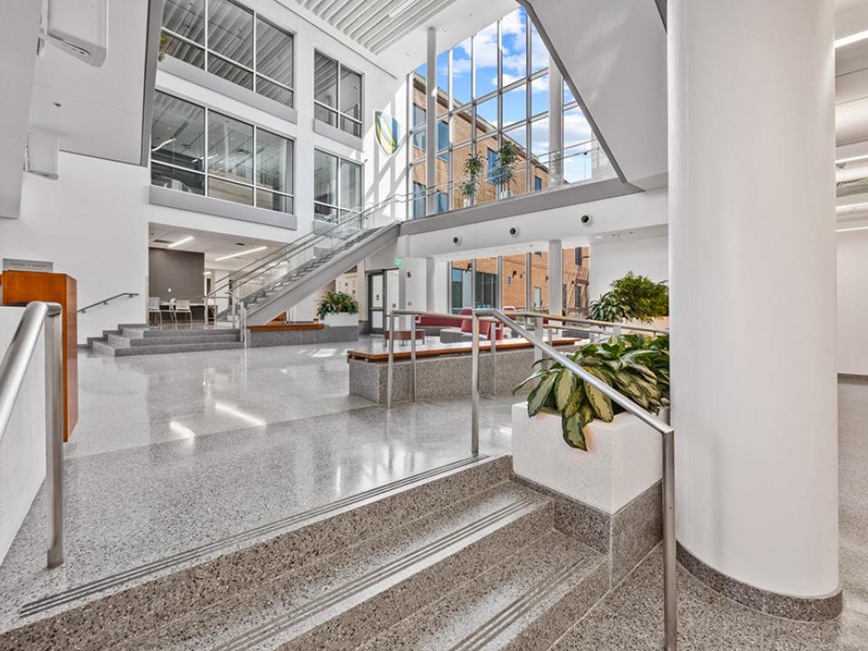 Business building lobby open space with multistory windows and wrap around stairs leading to the upper levels