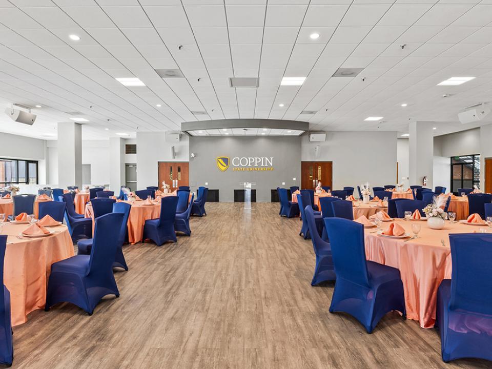 View of the Tawes Ballroom from the back center. Stage area is in the background and tables are to the left and right