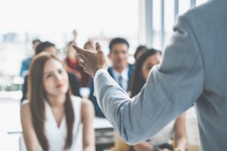 A person in a suit gives a presentation in front of an audience