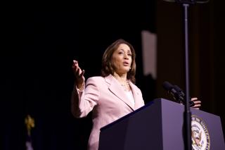 Vice President Kamala Harris stands at podium in pink suit